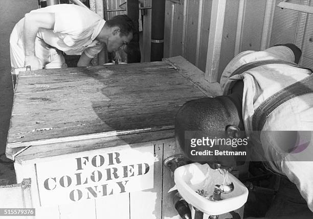 Segregated drinking fountain in use in the American South. Undated photograph. Sign reads "For colored only."