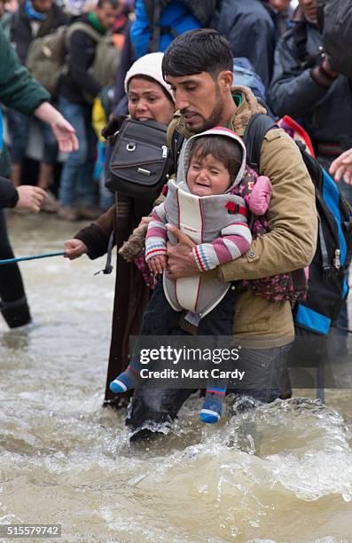 Migrants cross a river after leaving the Idomeni refugee camp on March 14, 2016 in Idomeni, Greece. The decision by Macedonia to close its border to...