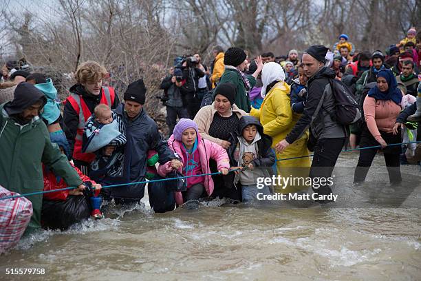 Migrants cross a river after leaving the Idomeni refugee camp on March 14, 2016 in Idomeni, Greece. The decision by Macedonia to close its border to...