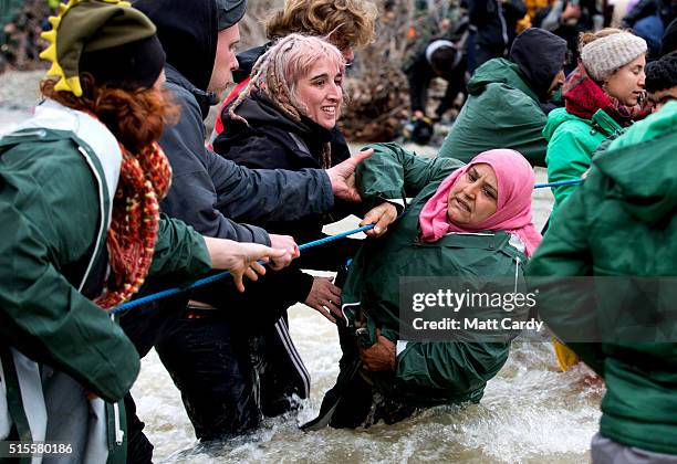 Migrants cross a river after leaving the Idomeni refugee camp on March 14, 2016 in Idomeni, Greece. The decision by Macedonia to close its border to...