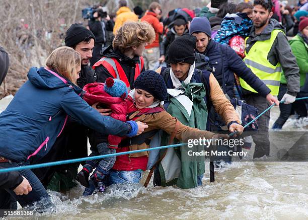 Migrants try to cross the river after leaving the Idomeni refugee camp on March 13, 2016 in Idomeni, Greece. The decision by Macedonia to close its...