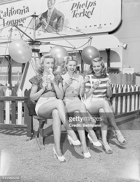 Movie actress Patty Thomas, Sandra Spence, and Dorothy Abbot cool off on a bench in a Santa Monica amusement park.