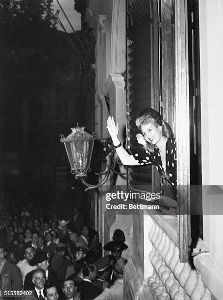 Eva Peron waves from her room in the Argentine Embassy to cheering crowds below.