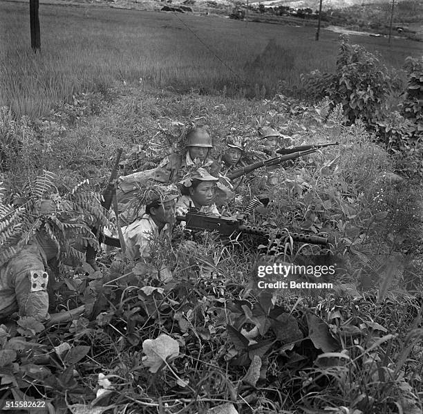 South Korea: Two girl guerrillas, Chong Sunjin and Hao Chi Okk, man a machine gun in the South Korean fields, alongside guerrillas armed with rifles....