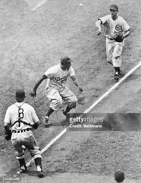 Third baseman Andy Pafko tosses the ball to catcher Rube Walker as the two trap base runner Jackie Robinson between third base and home in a game...