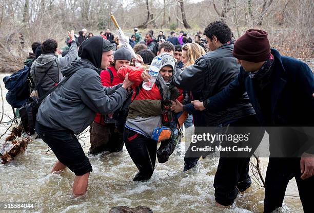 Migrants try to cross a river after leaving the Idomeni refugee camp on March 13, 2016 in Idomeni, Greece. The decision by Macedonia to close its...