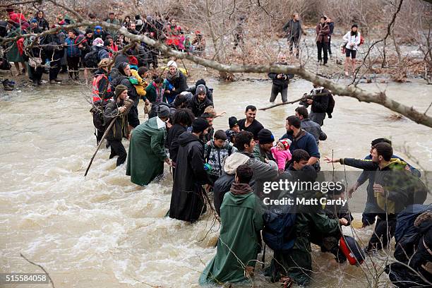 Migrants try to cross a river after leaving the Idomeni refugee camp on March 13, 2016 in Idomeni, Greece. The decision by Macedonia to close its...