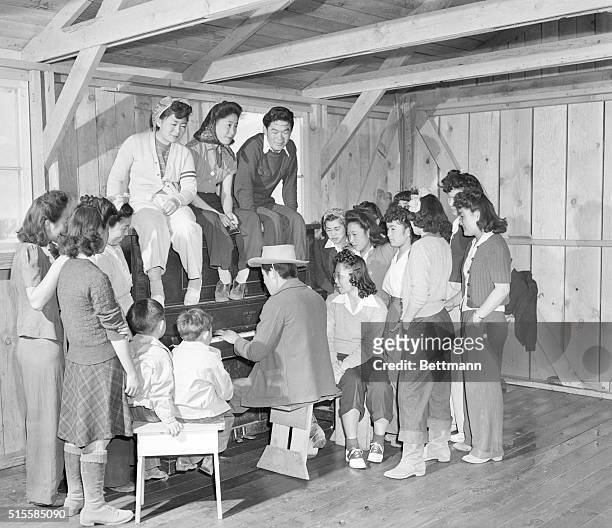 Group of Japanese Americans gathered round a piano at Manzanar War Relocation Center, an internment camp in Manzanar, Owens Valley, California, 5th...