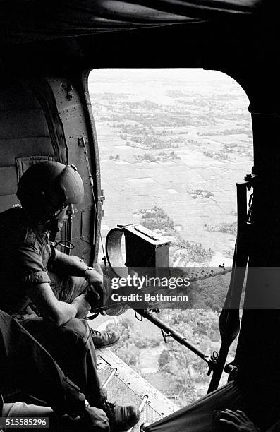 Quang Ngai Province, South Vietnam: An American soldier keeps watch from airborne helicopter carrying Vietnamese troops over marshlands south of...