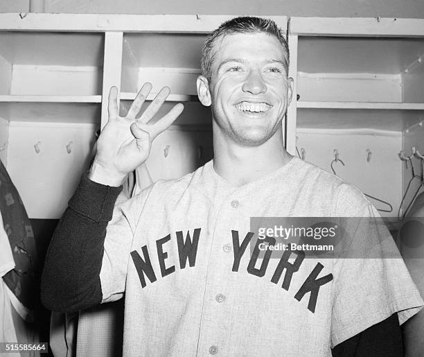 New York Yankee baseball player Mickey Mantle holds up four fingers in the locker room at Ebbets Field to signify the four runs that resulted from...