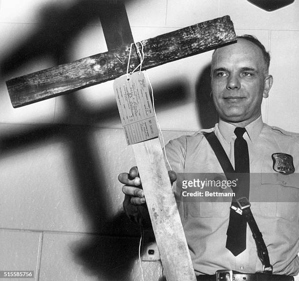 Detroit, MI: Patrolman John Krok displays the burnt cross that was found in front of the home of Anthony Liuzzo here early 4/3. Mr. Liuzzo is the...