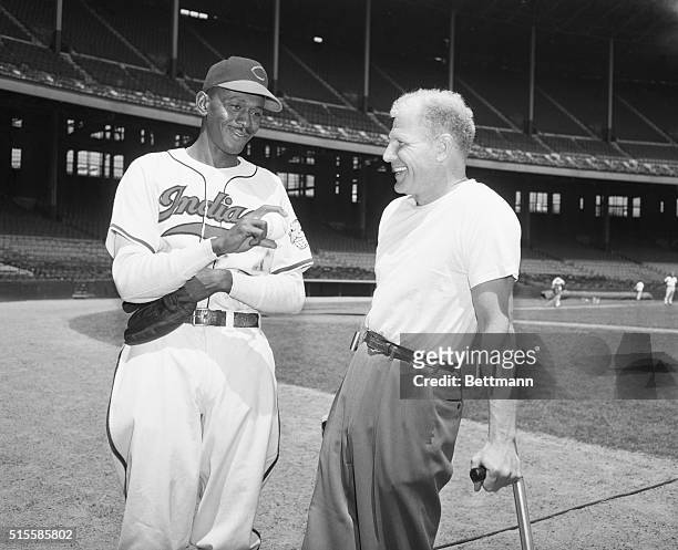 Cleveland Indians owner and president Bill Veeck, Jr., on crutches, talks to pitcher Satchel Paige. Paige just joined the Indians after a long career...