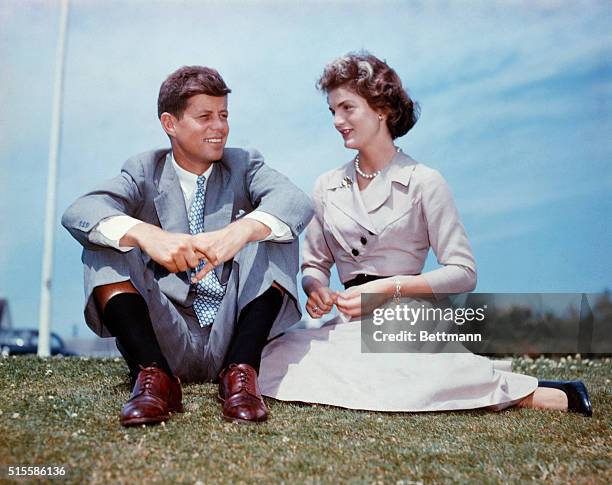 John F. Kennedy and Jacqueline Bouvier sit together in the sunshine at Kennedy's family home at Hyannis Port, Massachusetts, a few months before...