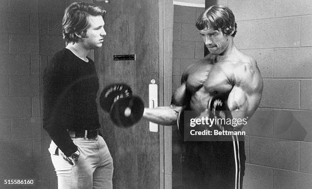 April 1976- Jeff Bridges and Arnold Schwarzenegger who is lifting weights in a movie still from "Stay Hungry".