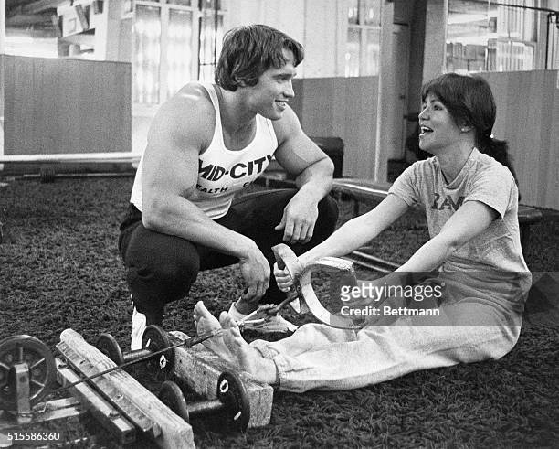 New York, NY: Actress Sally Field being trained by bodybuilder Arnold Schwarzenegger on the rowing machine.