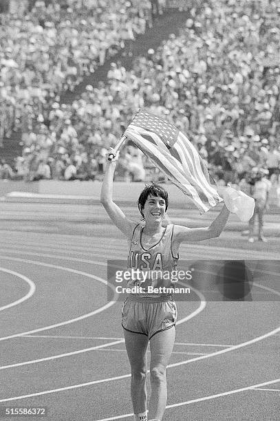 Los Angeles, CA- American runner Joan Benoit jogs around the Los Angeles Coliseum track carrying the American flag, after winning the gold medal in...
