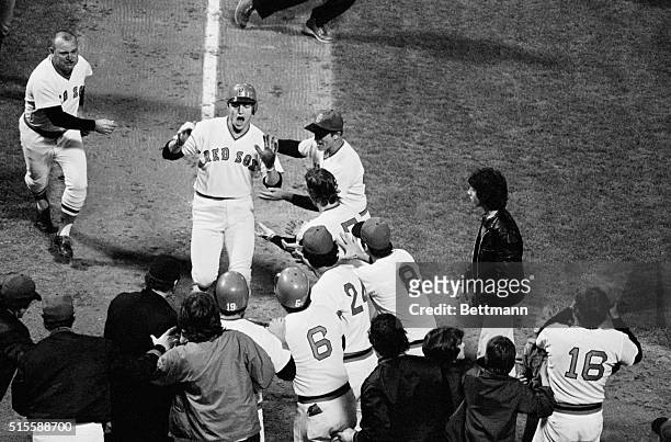 Red Sox catcher Carlton Fisk is greeted by his teammates at home plate after hitting the scoring run in game 6 of the 1975 World Series against the...