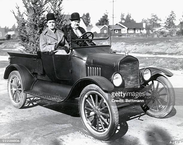 Comedic duo Laurel and Hardy sit in a Model T Ford with a Christmas tree on the set of Big Business.