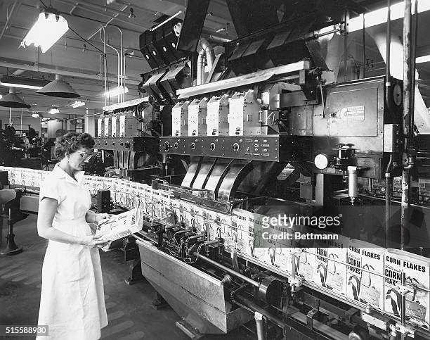 Woman inspects a Corn Flakes cereal box along the conveyor belt at the Corn Flakes division of Kellogg's main packaging plant.