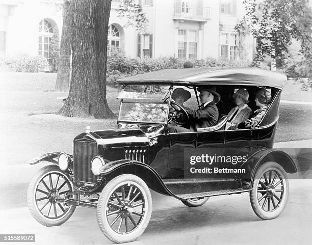 Pictyre shows a ford touring car with passengers in it.