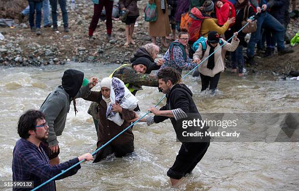 Migrants try to cross a river after leaving the Idomeni refugee camp, on March 14, 2016 in Idomeni, Greece. The decision by Macedonia to close its...