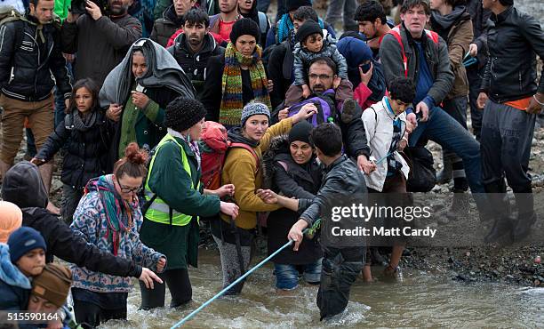 Migrants try to cross a river after leaving the Idomeni refugee camp, on March 14, 2016 in Idomeni, Greece. The decision by Macedonia to close its...