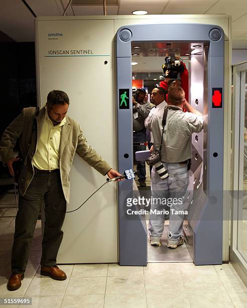 Reporters and photographers record sounds and images of a new explosive detection walk-through device at a passenger security checkpoint at John F....