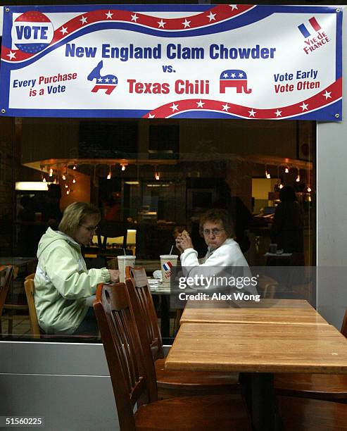 Two women are seen eating at a Vie de France restaurant, as a banner which shows the choices of soups is hung above October 25, 2004 in Washington,...