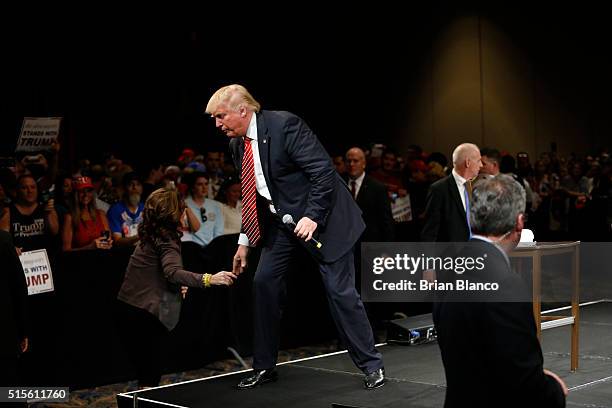 Republican presidential candidate Donald Trump shakes hands with former Alaska governor Sarah Palin after speaking to supporters during a town hall...