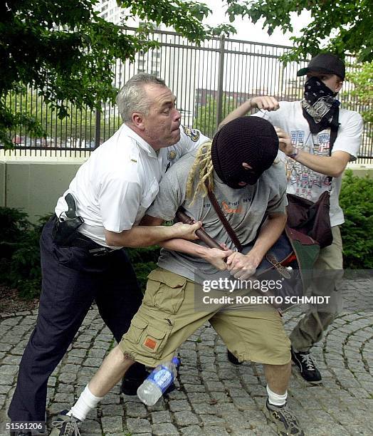 Philadelphia city policeman tries to defend himself as he is attacked by hooded protesters after the officer tried to catch running demonstrators and...