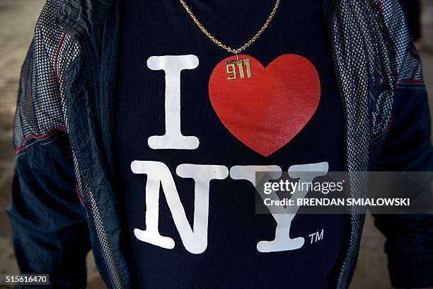 Man wears a 9-11 necklace and an "I Love New York" shirt while waiting for a rally with US Republican presidential hopeful Donald Trump on March 14,...