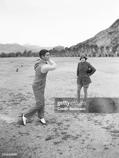 The Missus Watches Him Golf. Palm Springs, Cal.: While Mrs. Gable, in riding habit stands by, Clark Gable, screen heart breaker takes a swipe at the...