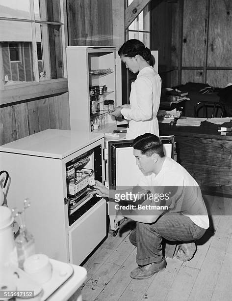 Manzanar, California: Dr. James Goto, former resident physician at Los Angeles County Hospital and his nurse, Fumiko Gohata, prepare for business at...