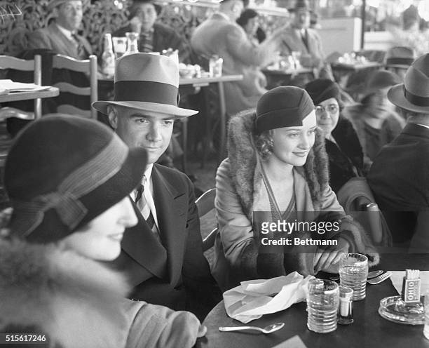 At the opening of the Agua Caliente Race Track on Christmas Day, is Howard Hughes, youthful millionaire motion picture producer, and Miss Marian...