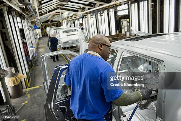 An employee uses a flash grinder to smooth out the metal frame of a sports utility vehicle on the production line at the General Motors Co. Assembly...
