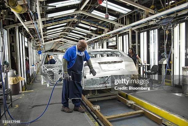An employee uses a flash grinder to smooth out the metal frame of a sports utility vehicle on the production line at the General Motors Co. Assembly...