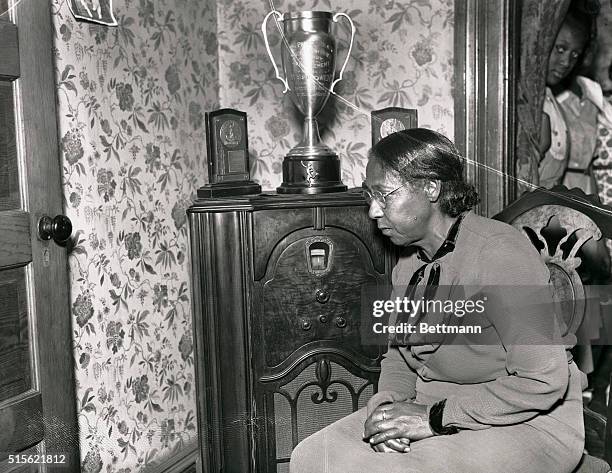 Proud mother, Mrs. Cleveland Owens, listens to a news report tell of her son's exploits at the Olympic games in Berlin, Germany. Her son Jesse, Negro...