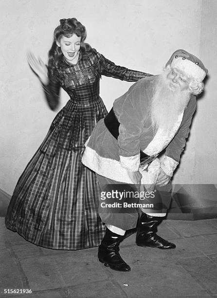 Hollywood, CA- Ida Lupino, Warner Brothers star, delivers a few wallops to Santa Claus' spankable rear extremity for, although you would never guess...