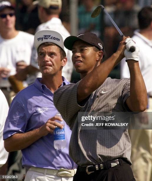 Golfer Tiger Woods of the US hits range balls from the practice area 15 August, 2000 as fellow player Jasper Parnevik of Sweden looks on before the...