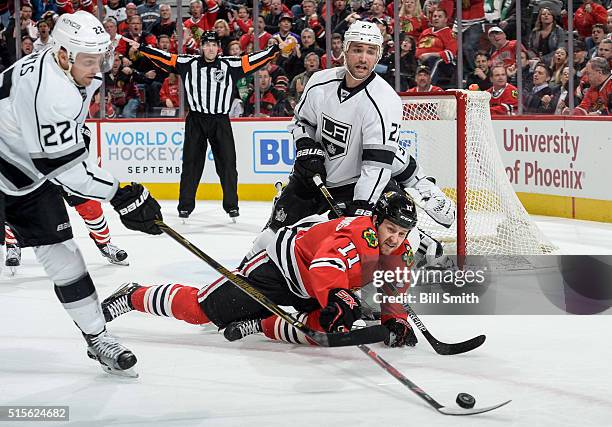 Andrew Desjardins of the Chicago Blackhawks reaches for the puck against Trevor Lewis and Alec Martinez of the Los Angeles Kings in the first period...