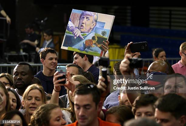 An attendee holds a painting of Donald Trump during a Get Out the Vote event event with democratic presidential candidate former Secretary of State...