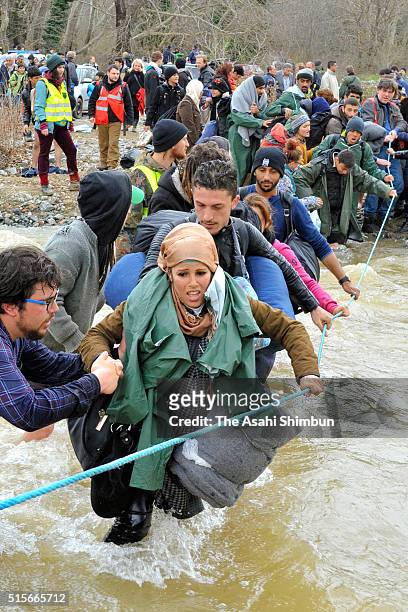 Migrants try to cross a river after leaving the Idomeni refugee camp on March 14, 2016 in Idomeni, Greece. The decision by Macedonia to close its...