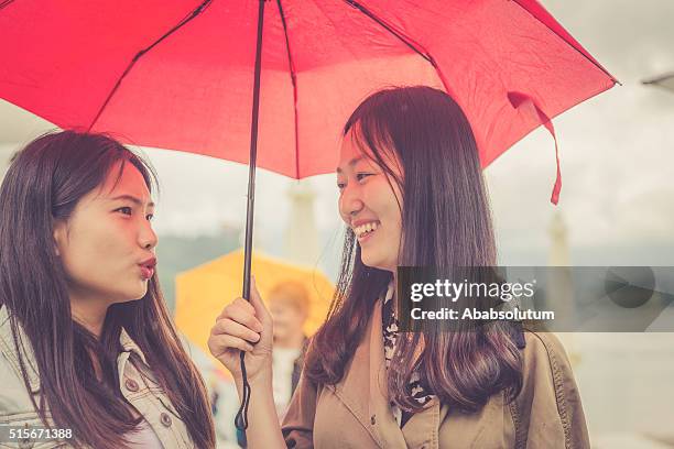 young chinese friends talking, rainy, bled, slovenia, europe - sharing umbrella stock pictures, royalty-free photos & images