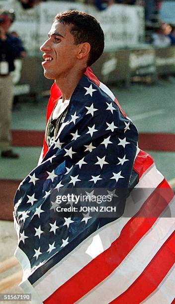 Chicago Marathon defending champion Khalid Khannouchi wraps himself in an American flag as he catches his breath after winning the marathon 22...