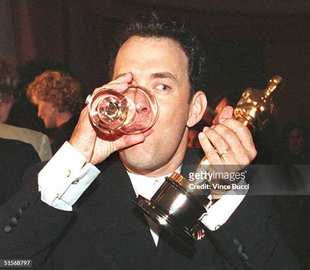 Actor Tom Hanks holds up his Oscar as he drinks a glass of water while attending the Governor's Ball after the 67th annual Academy Awards in Los...