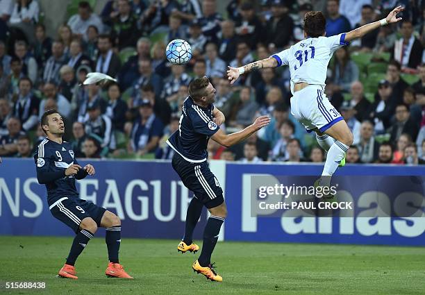 Kosta Barbarouses of Melbourne Victory eyes the ball as teammate Nicholas Ansell and Sin Se Gye Suwon of Samsung Bluewings leap during the AFC...