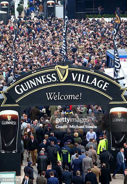 Racegoers walk through the Guinness Village before the start of day one, Champion Day, of the Cheltenham Festival at Cheltenham Racecourse on March...