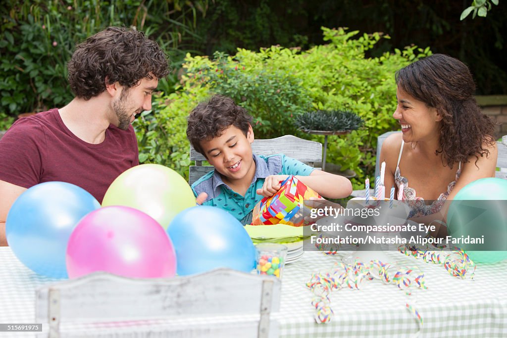 Boy opening present at birthday party