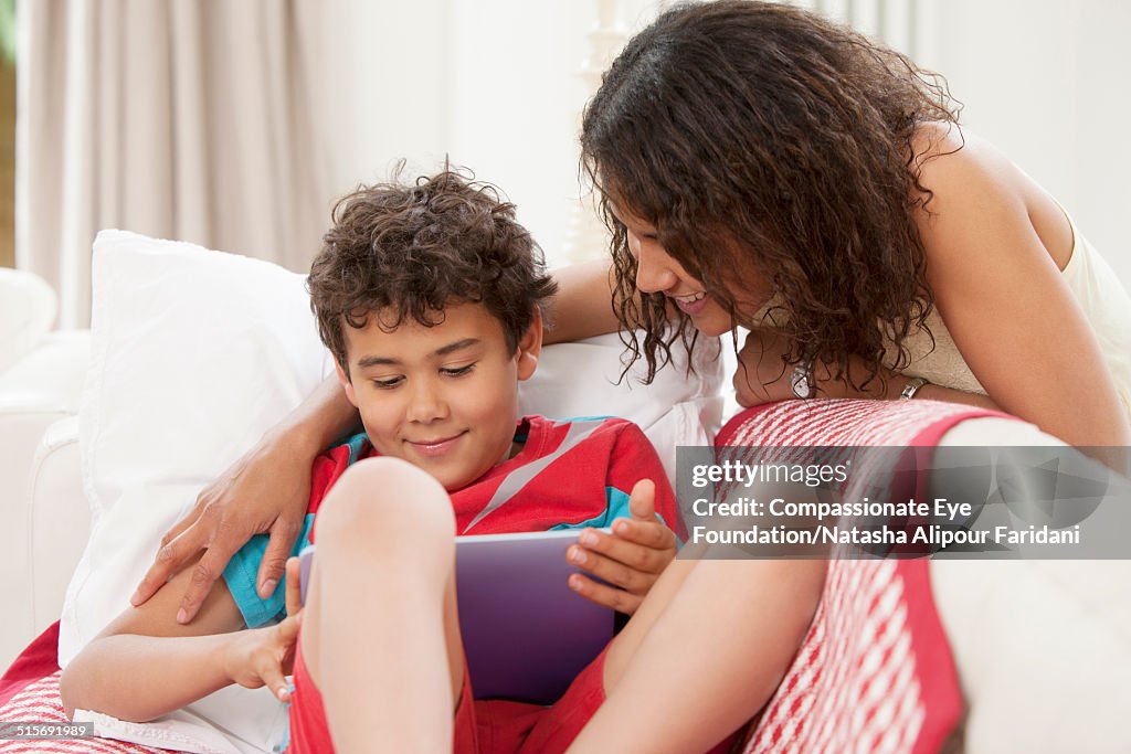 Mother and son using digital tablet in living room