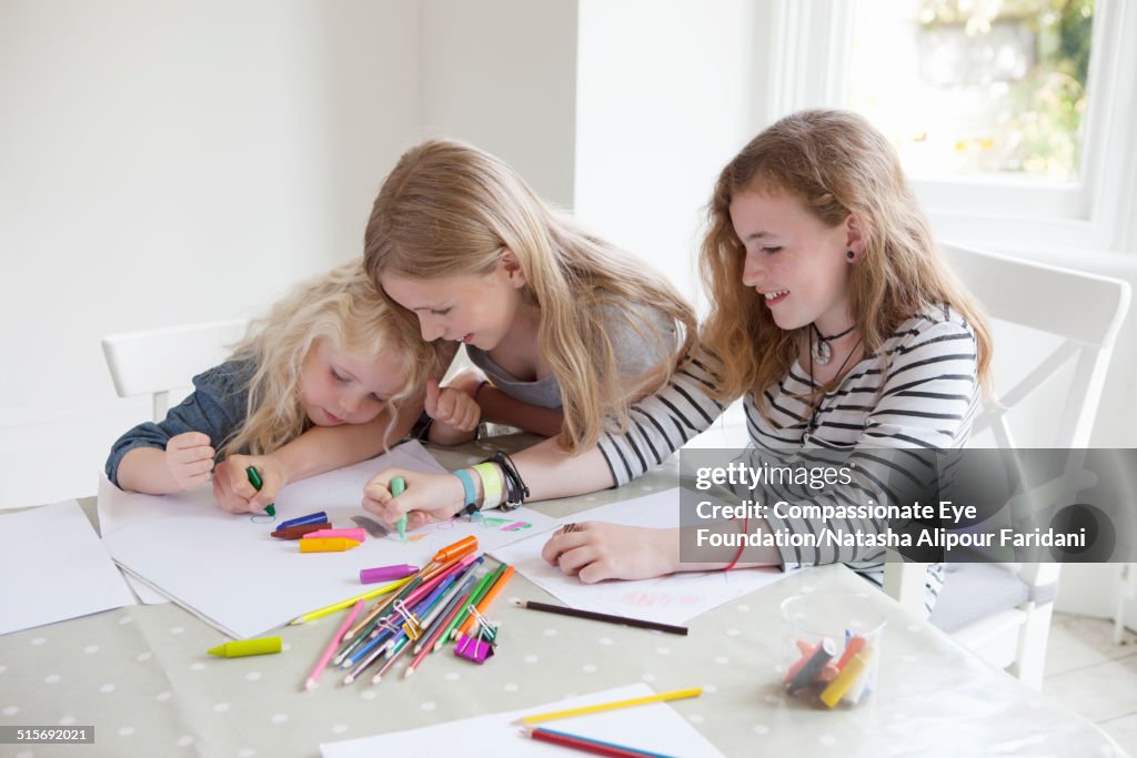 Three girls drawing with crayons